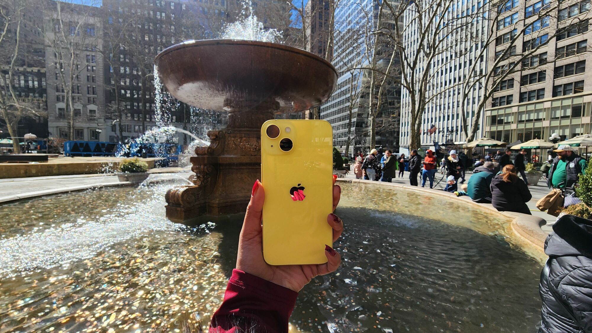 Yellow iPhone 15 with Bryant Park in the background