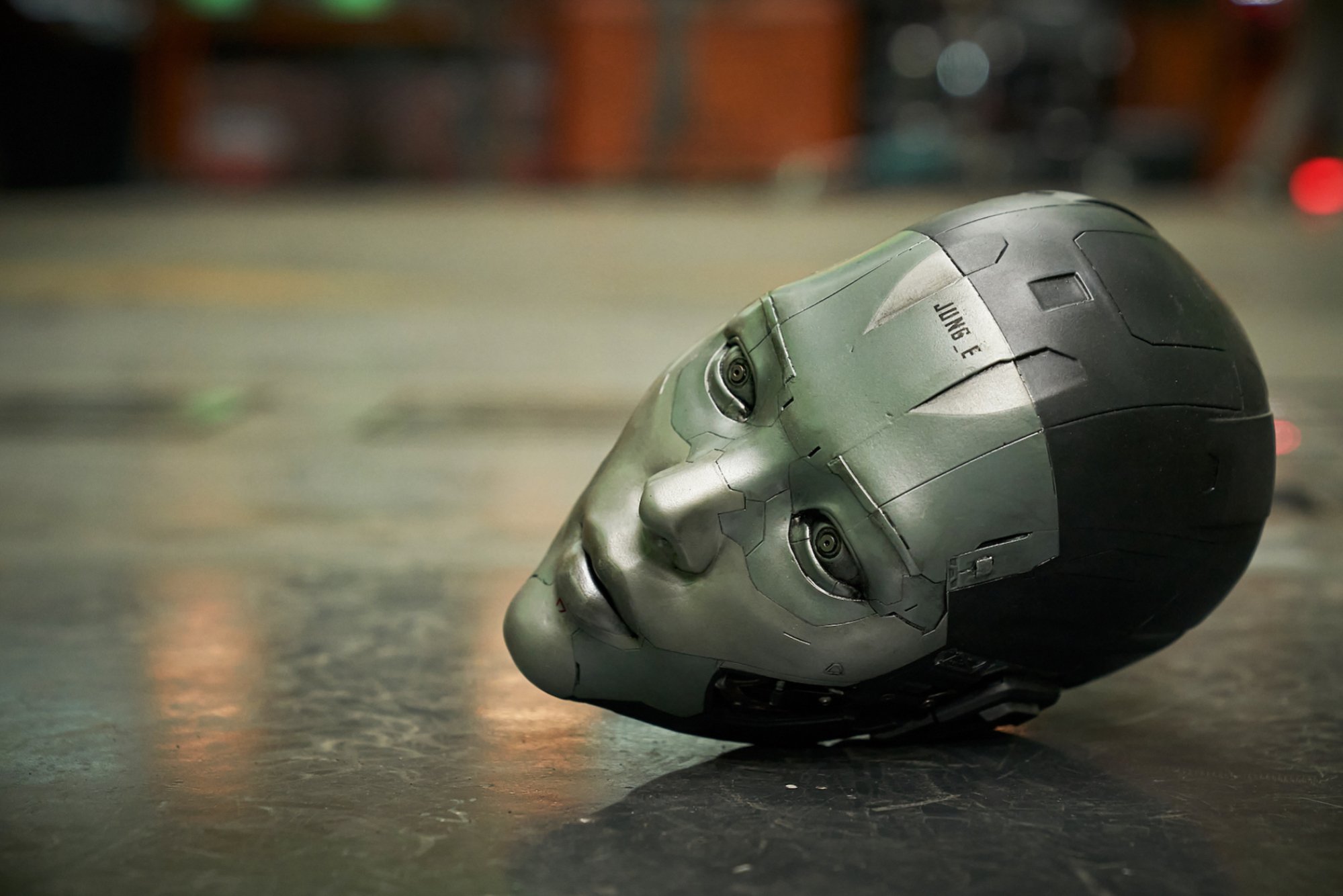 A disembodied head of a robot lies on the ground. 